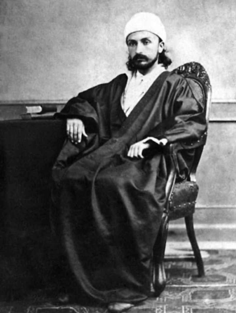 Young Abdu’l-Bahá sits in a chair
